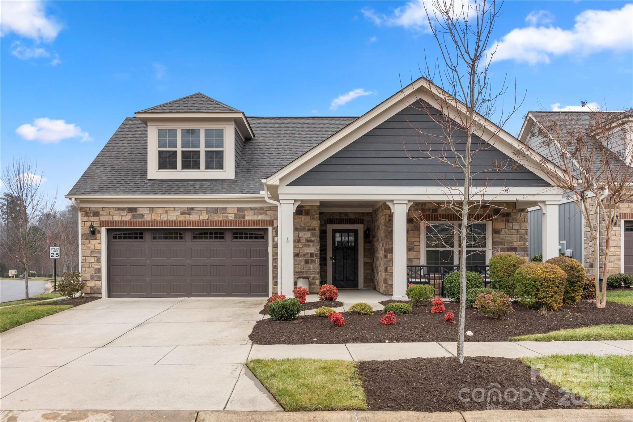 Attached townhome with stone siding, a two-car garage, and a covered front porch.