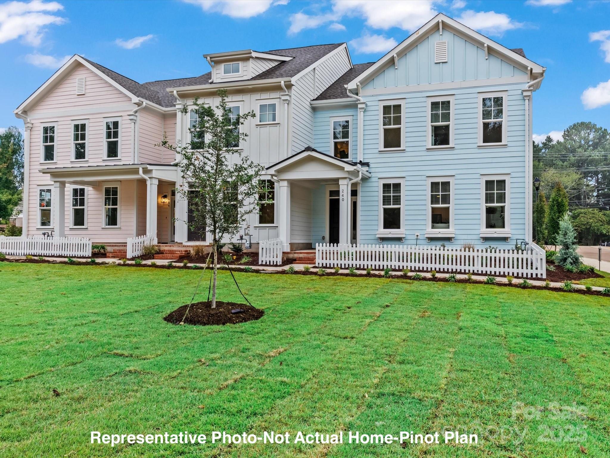 Attached pastel-sided townhomes behind white picket fences, with a broad front lawn.