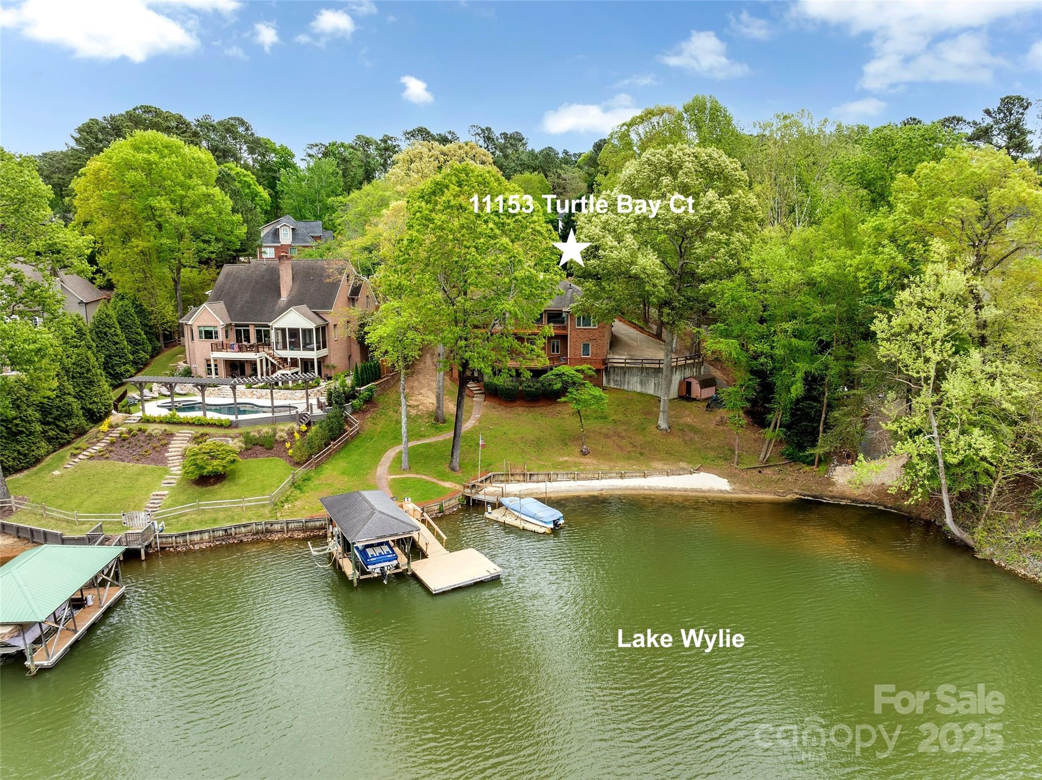 Aerial view of a wooded Lake Wylie waterfront home marked with a star, with a deck and dock.