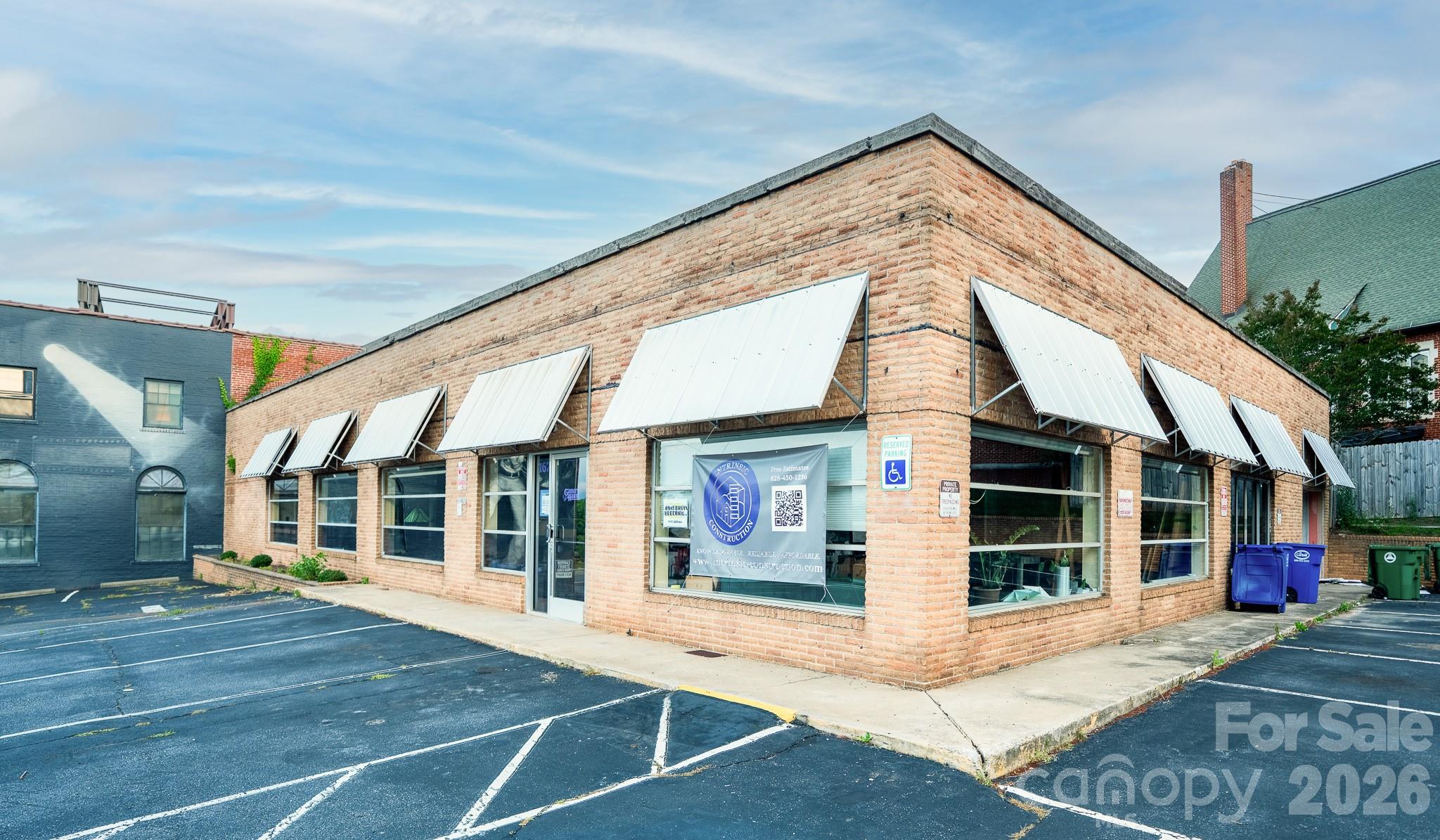 One-story brick commercial building with white awnings and a corner parking lot.