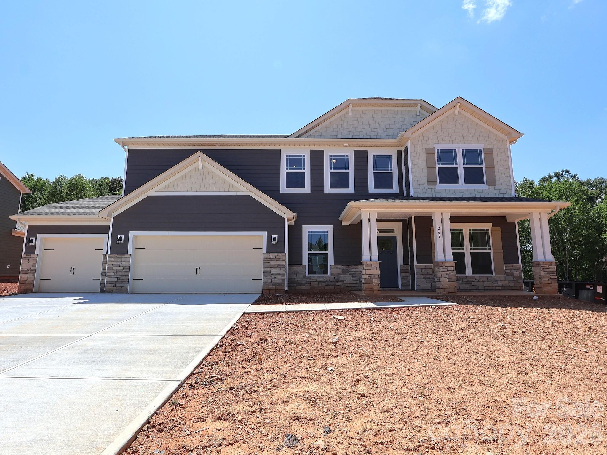 Two-story house with a covered porch, stone veneer, and a two-car garage.
