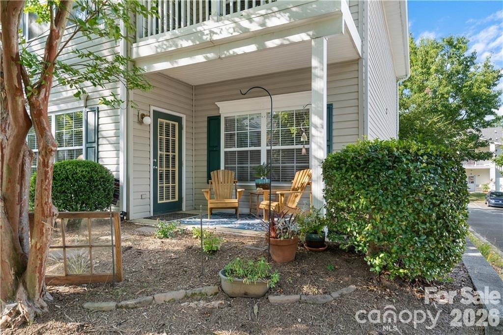 Condominium patio with green shutters, outdoor chairs, and mature landscaping.