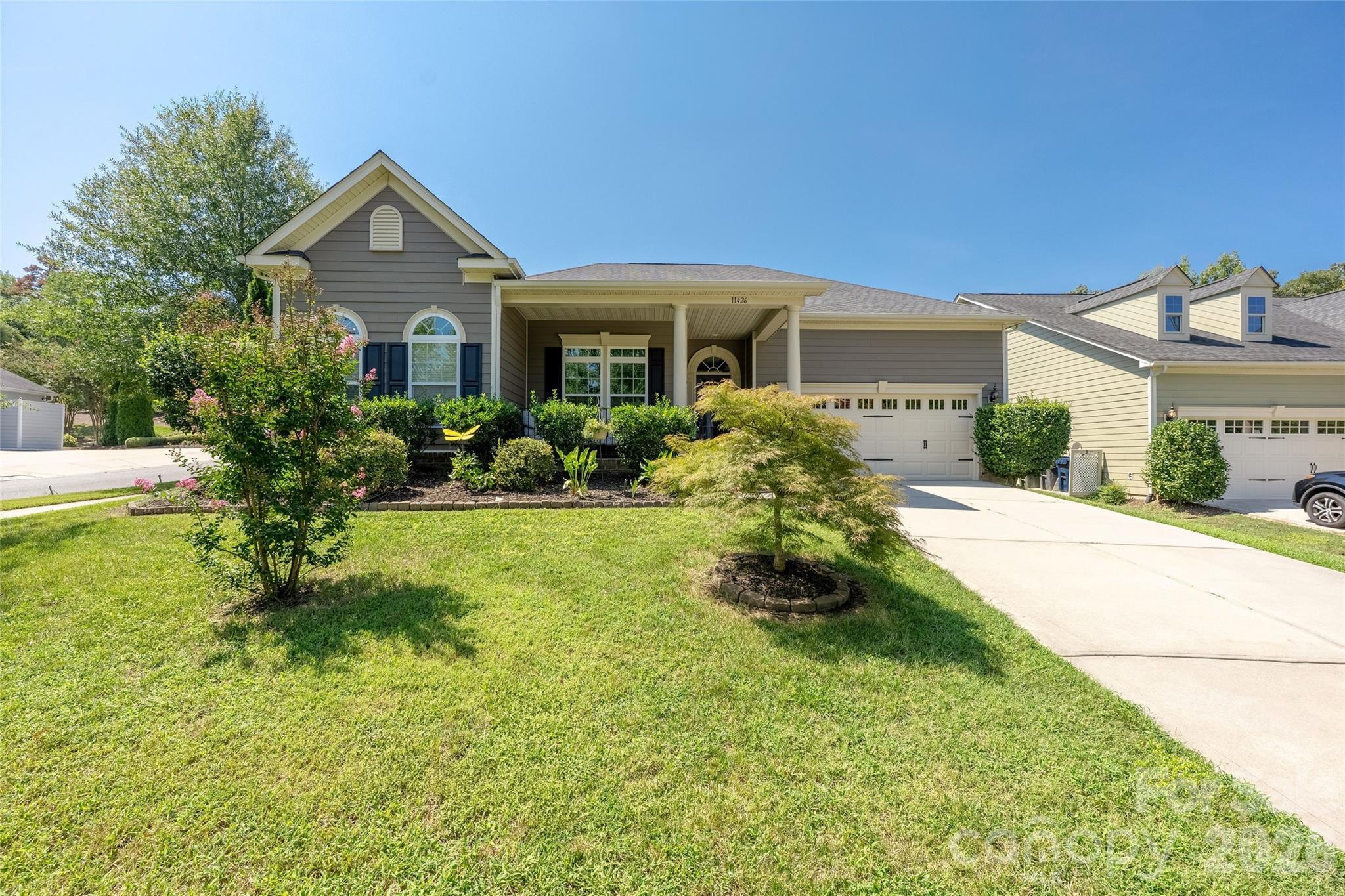 Gray-sided home with a covered porch, attached garage, and landscaped front yard.